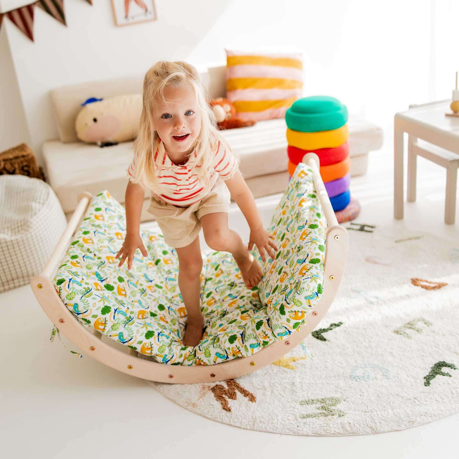 Mädchen spielt auf einem Kletterbogen mit buntem Kissen, entwickelt Geschicklichkeit und Spaß im Spielzimmer.