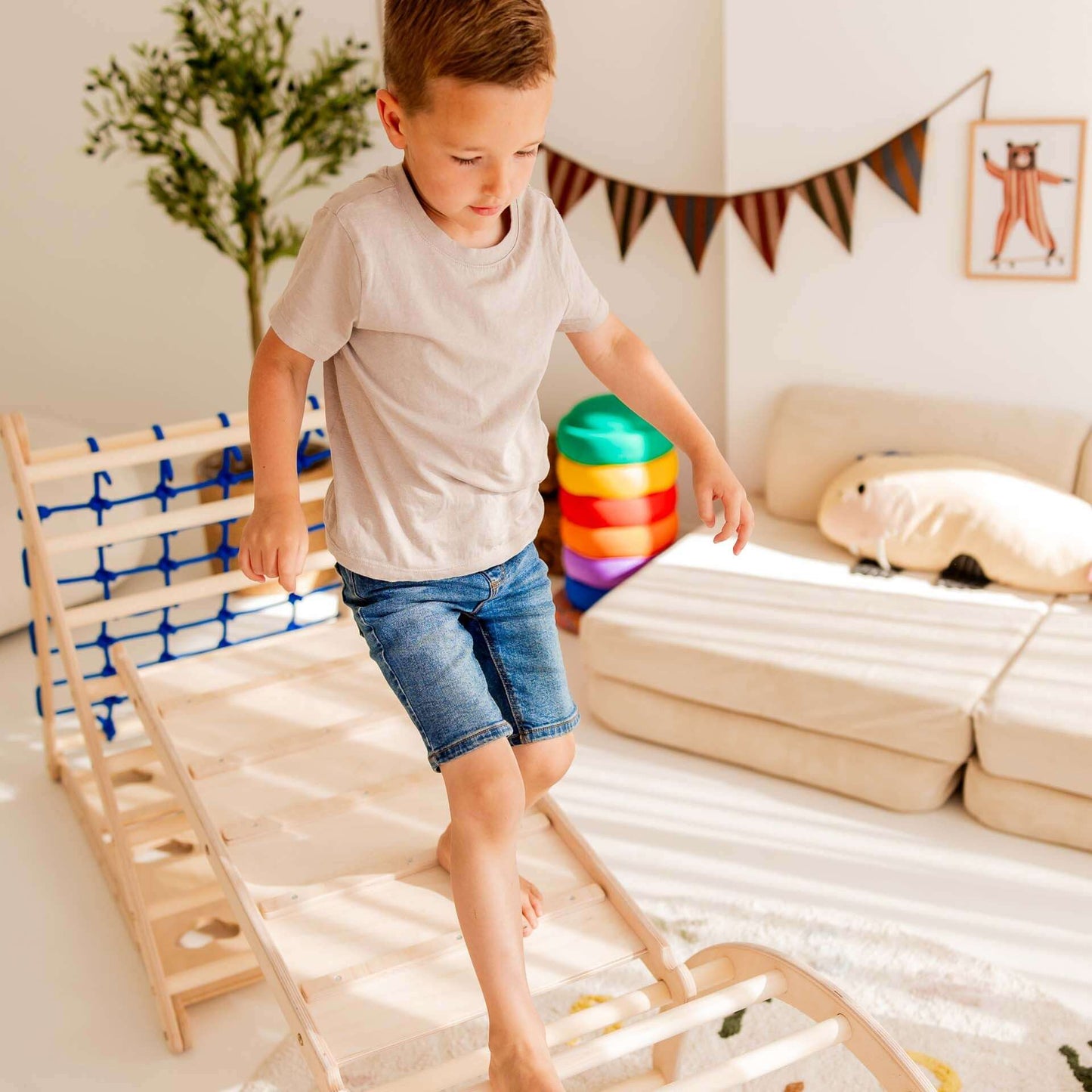 Junge klettert spielerisch auf dem Kletterset Löwe mit Kletterdreieck und Hühnerleiter in einem hellen Raum.