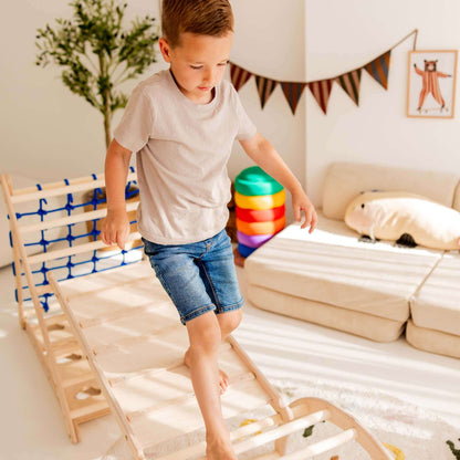 Junge klettert spielerisch auf dem Kletterset Löwe mit Kletterdreieck und Hühnerleiter in einem hellen Raum.