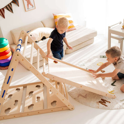Zwei Kinder spielen mit dem Kletterset Löwe aus Holz, bestehend aus Kletterdreieck und Rutsche im hellen Raum.