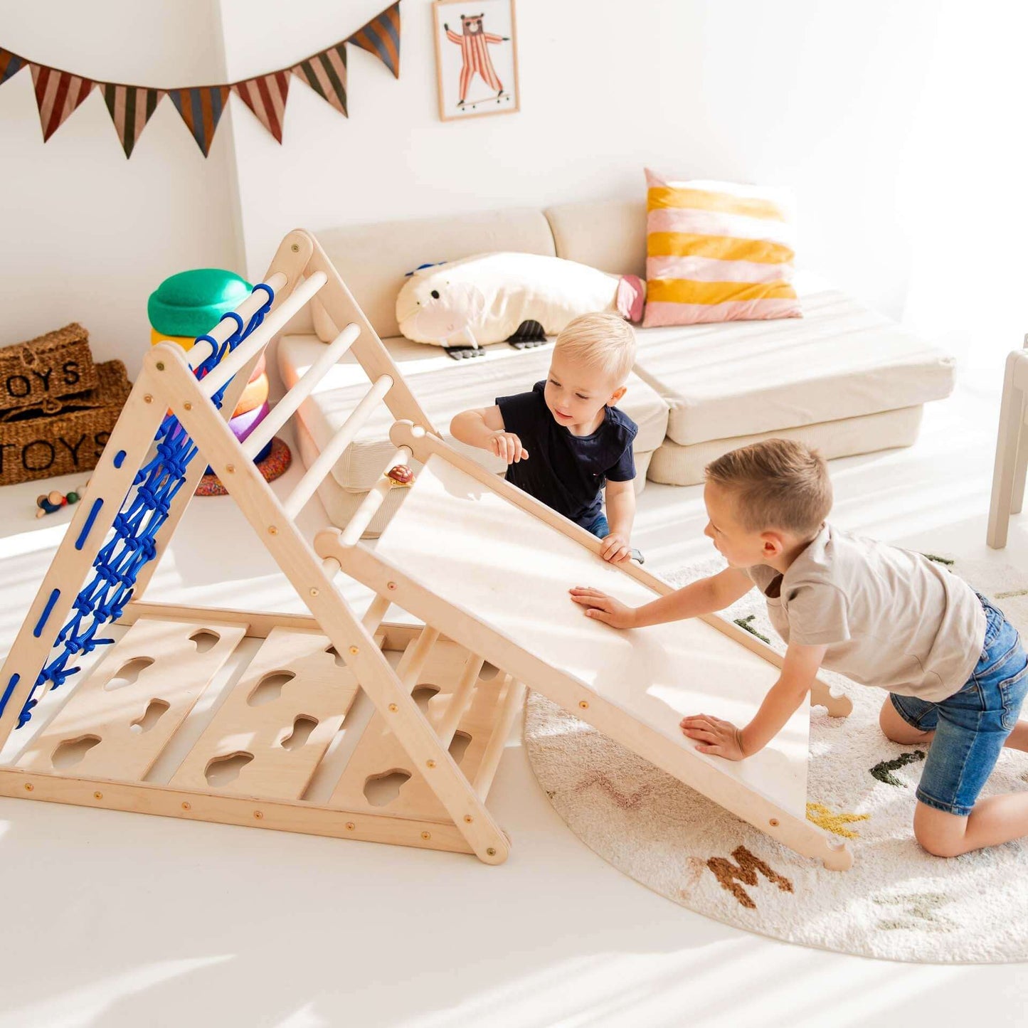 Zwei Kinder spielen mit dem Kletterset Löwe: Kletterdreieck, Rutsche und Hühnerleiter aus Holz im hellen Raum.