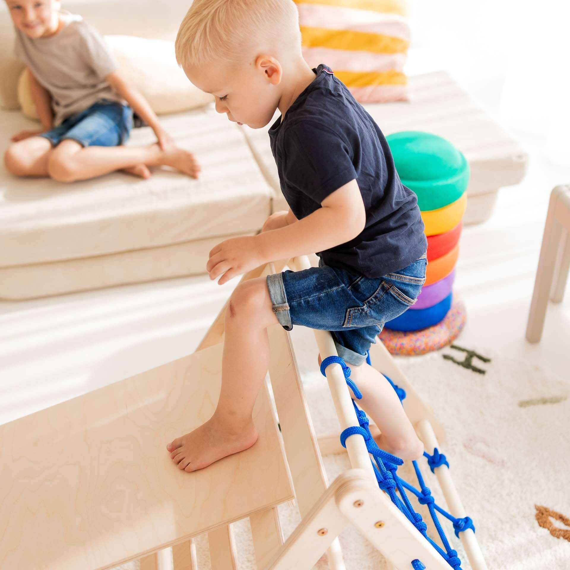 Kletterset Kleiner Tiger: Kind klettert auf Kletterdreieck mit Kletternetz, spielend seine Bewegungsfähigkeiten entwickelnd.