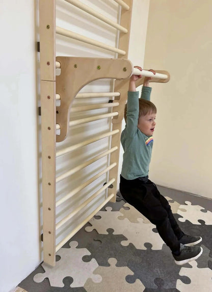 Kletterwand für Kinder aus Holz, Kleinkind übt Klimmzüge an Sprossenwand im Spielzimmer.