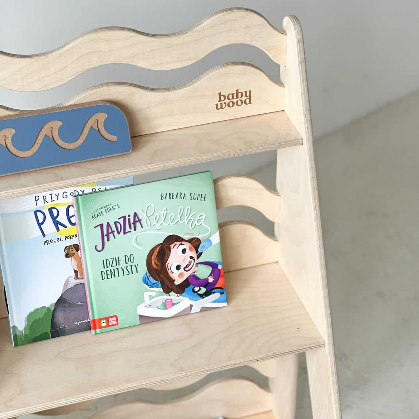 Spielzeugregal "WAVE" aus Holz, versch. Größen mit bunten Büchern und sanften Wellenlinien.
